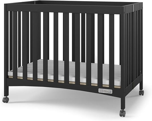 Child Craft London Mini Compact Folding Portable Crib with 2” Crib Mattress and 2 Easy Roll Locking Wheels, Durable Pine Wood Construction (Ebony Black)